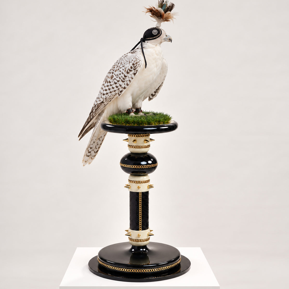 EMPRESS, The Sovereign Domain Falcon Perch by FUROAR, featuring a hooded falcon on a black, ivory and gold luxury perch with chain detailing, sculptural accents and a grass-covered platform.
