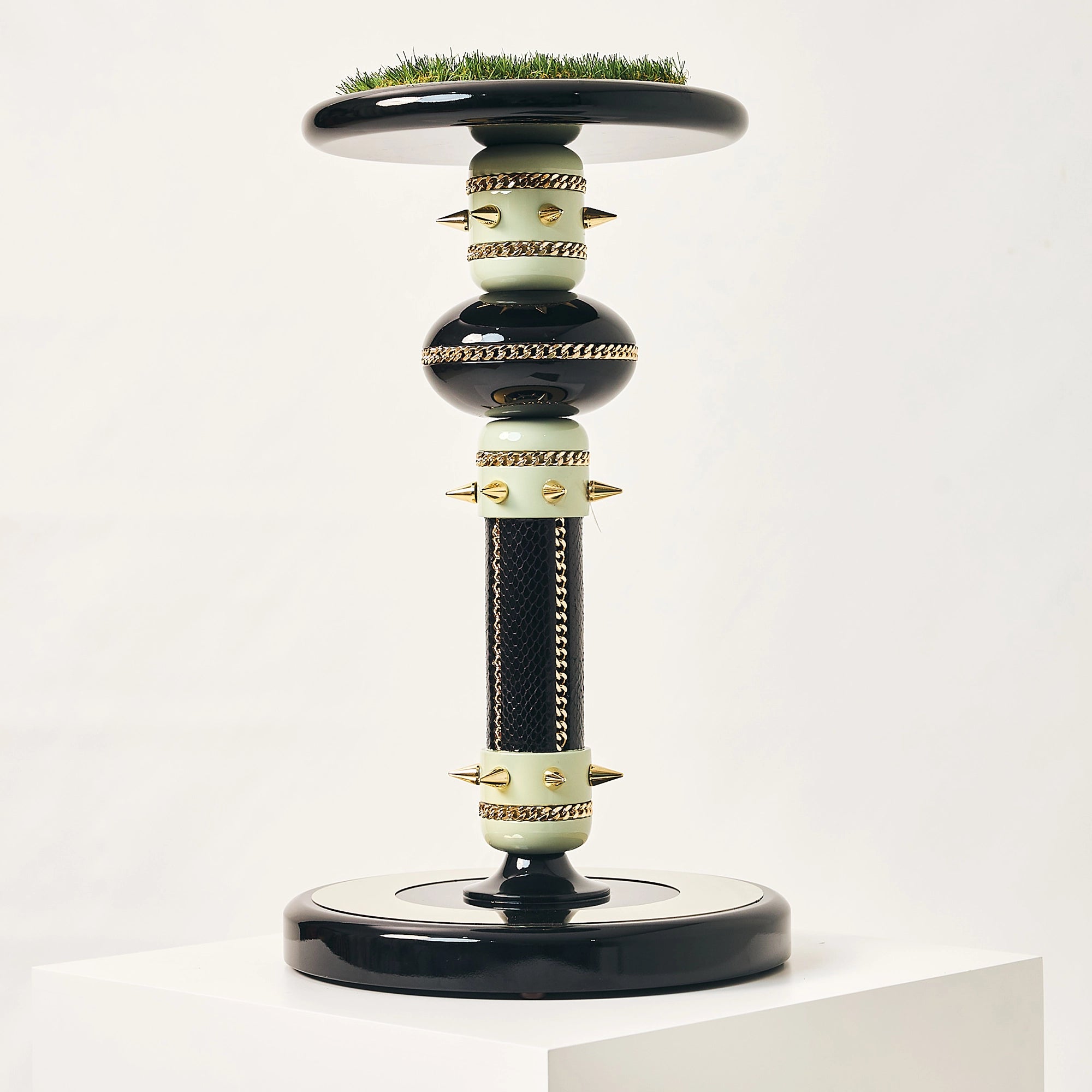 The black and gold Empress falcon stand by FUROAR showing a green grass top and column.