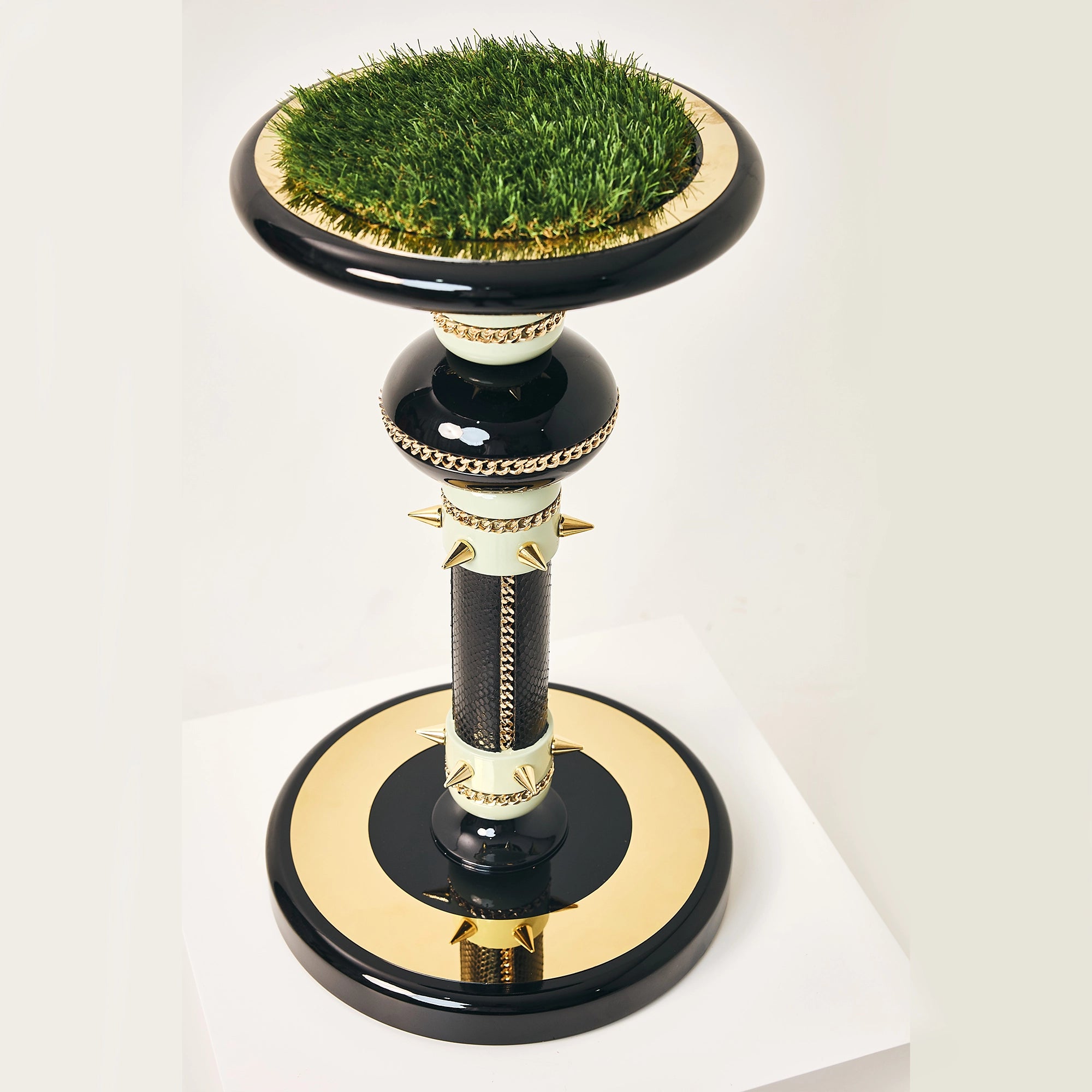 The Empress falcon stand by FUROAR featuring a gold-paneled base and turf landing pad.
