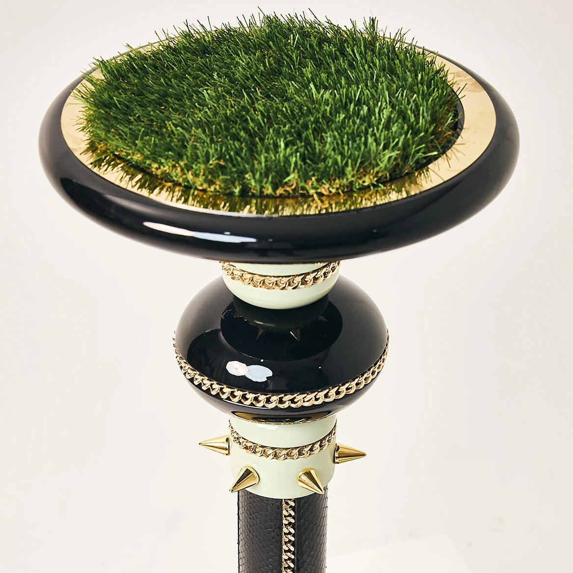 The Empress falcon stand by FUROAR featuring a gold-paneled base and turf landing pad.