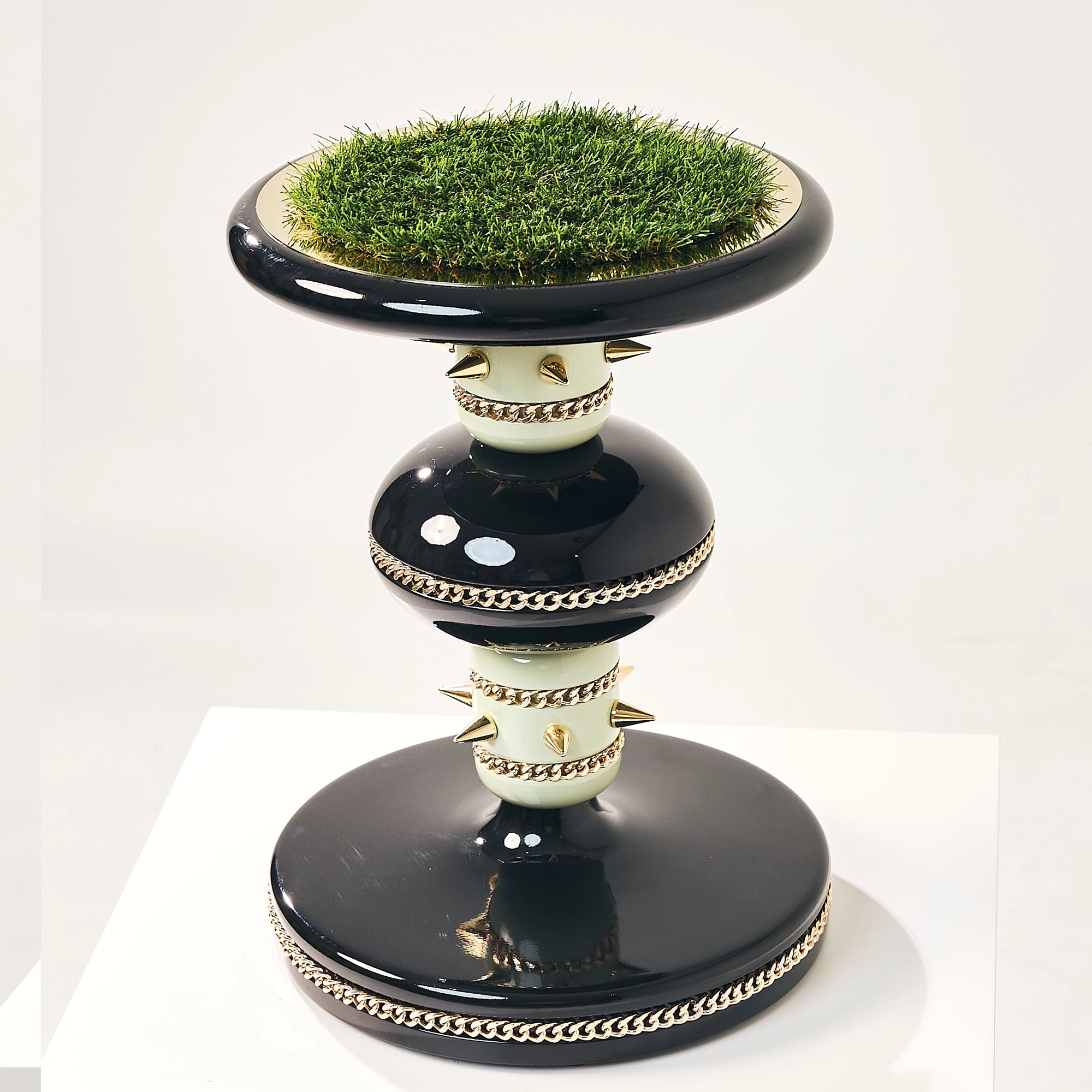 The Skye falcon stand by FUROAR featuring a gold-chained base and turf landing pad.