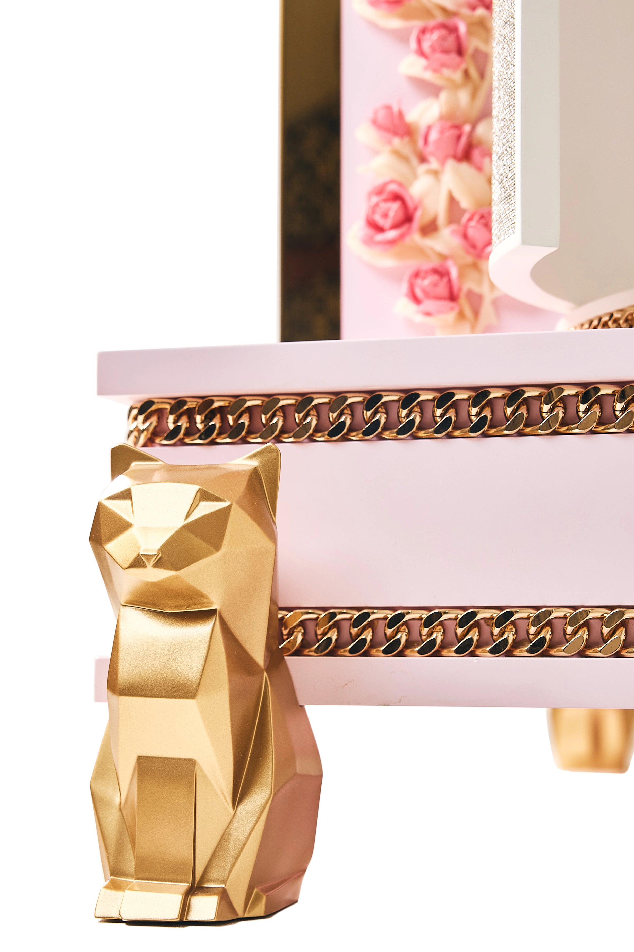 lose-up of the FUROAR Bella cat villa showcasing a geometric gold cat sculpture leg, metallic curb chain trim, and delicate pink rose accents.