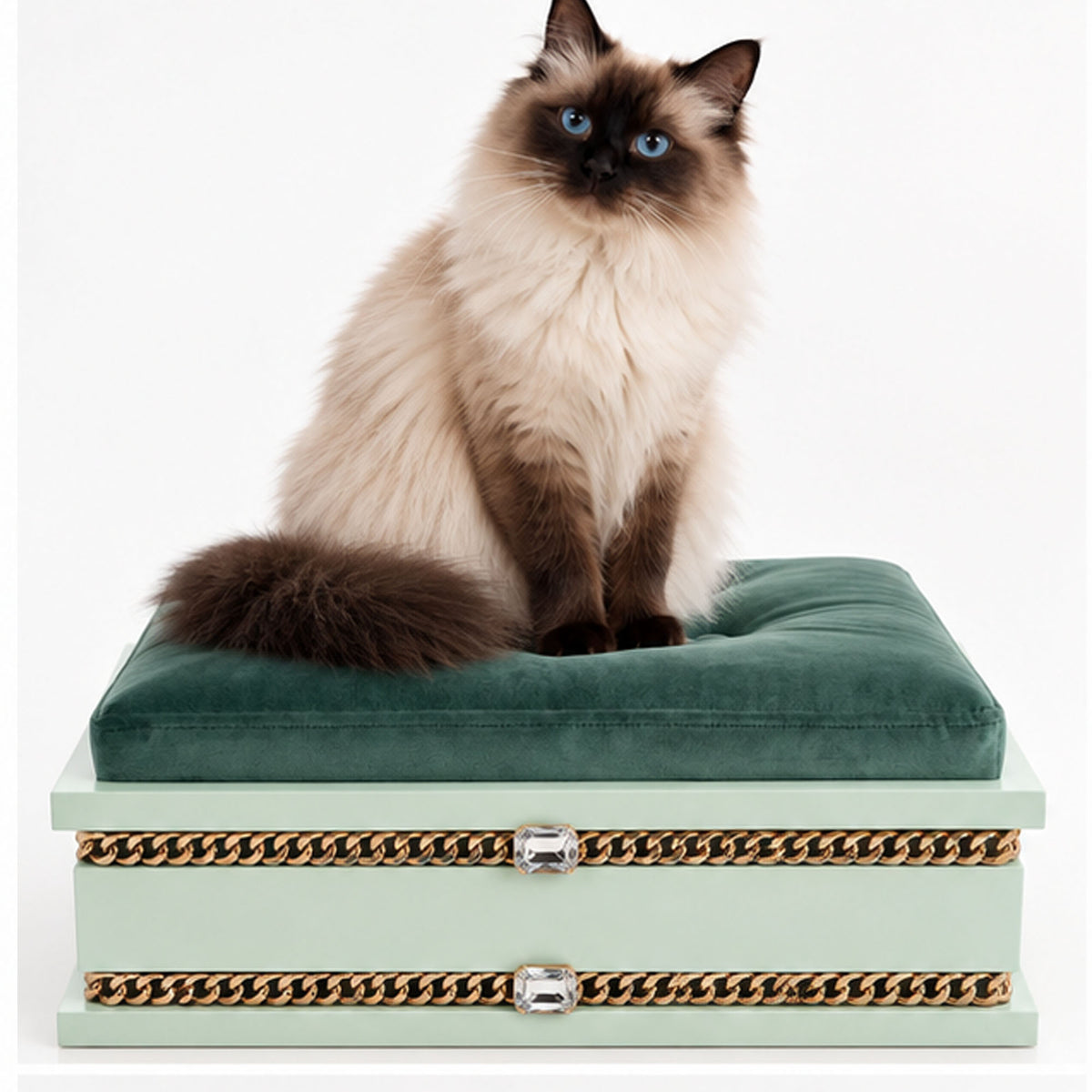 Long-haired Siamese cat sitting on a FUROAR Ivy luxury cat bed with green velvet cushion and gold chain detailing.