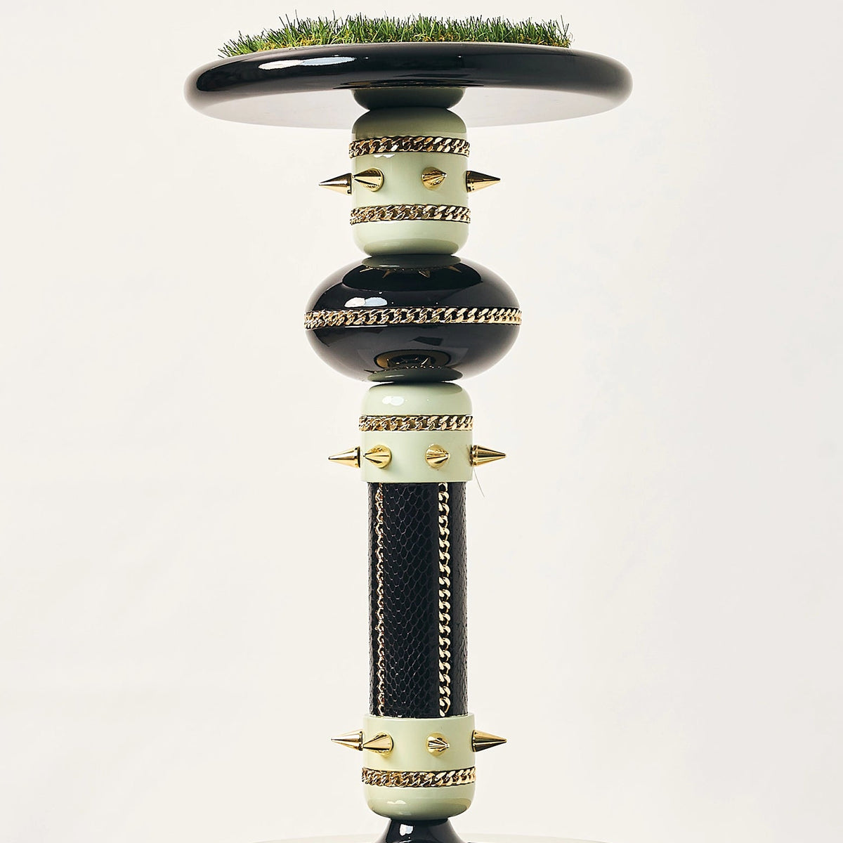 The black and gold Empress falcon stand by FUROAR showing a green grass top and column.