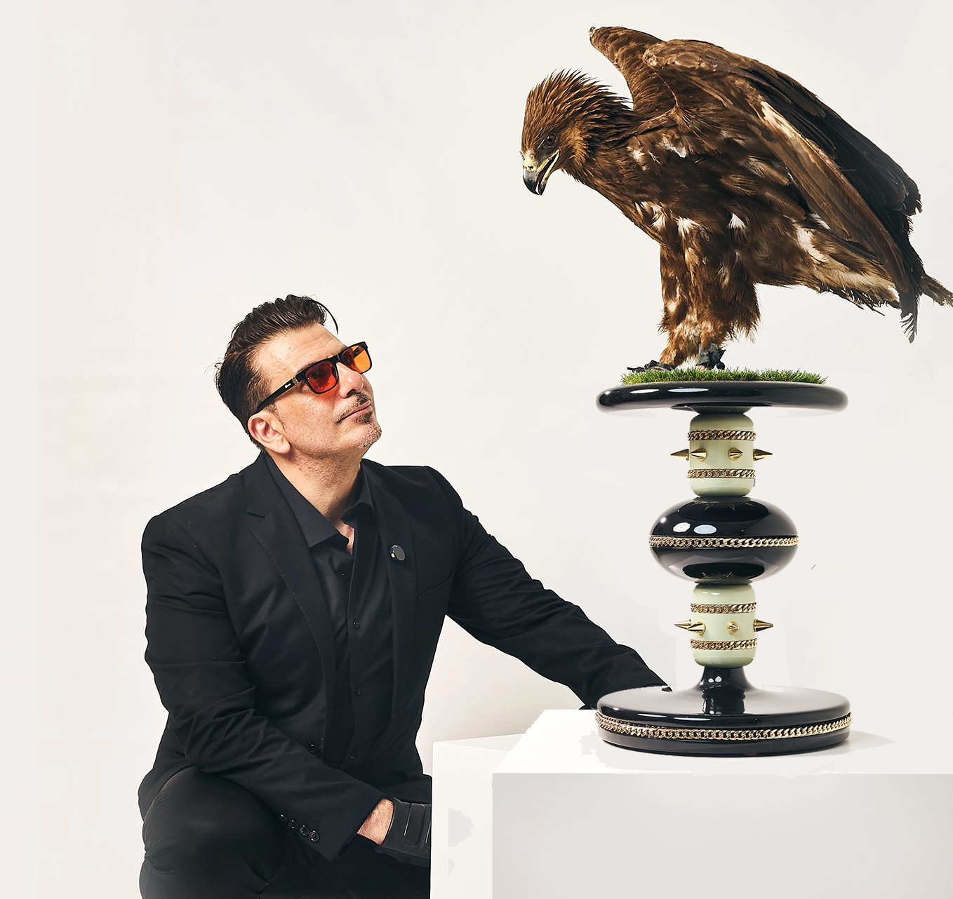 A golden eagle on the luxury FUROAR Skye falcon perch next to a man in a black suit.