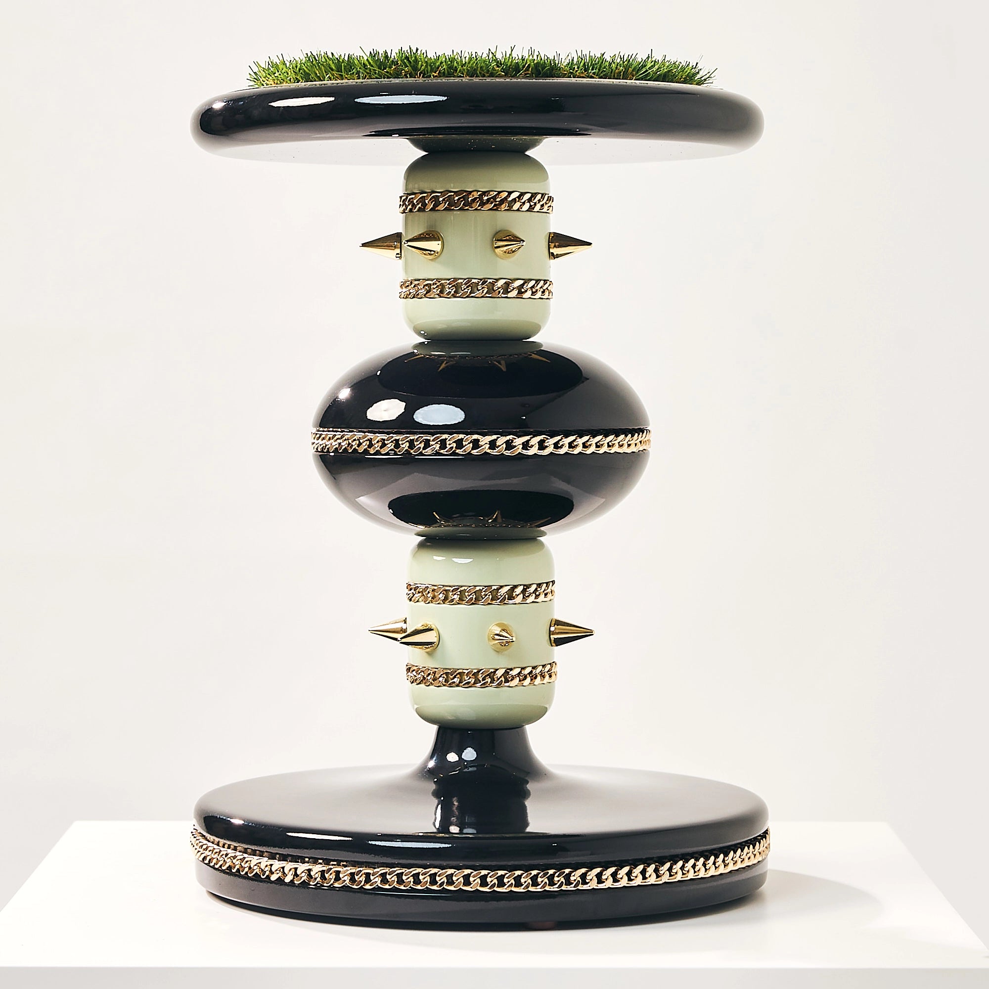 The black and gold Skye falcon stand by FUROAR showing a green grass top and pillars.