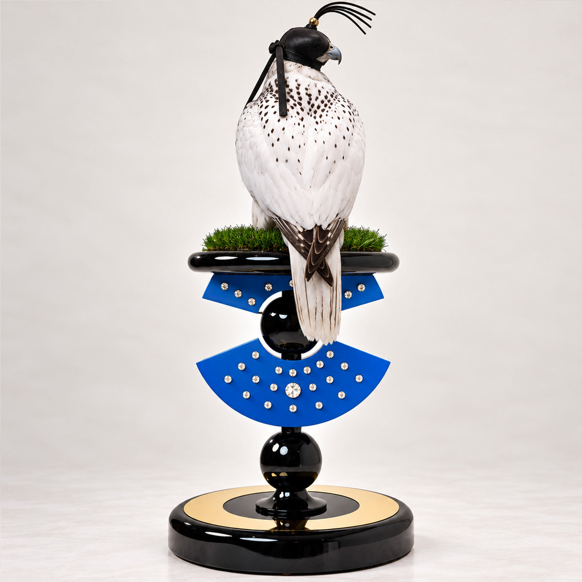 ZANOBIAR, The Legendary Queen Falcon Perch by FUROAR, featuring a sculptural blue and black design with crystal detailing, green grip grass and a white falcon wearing a black hood.