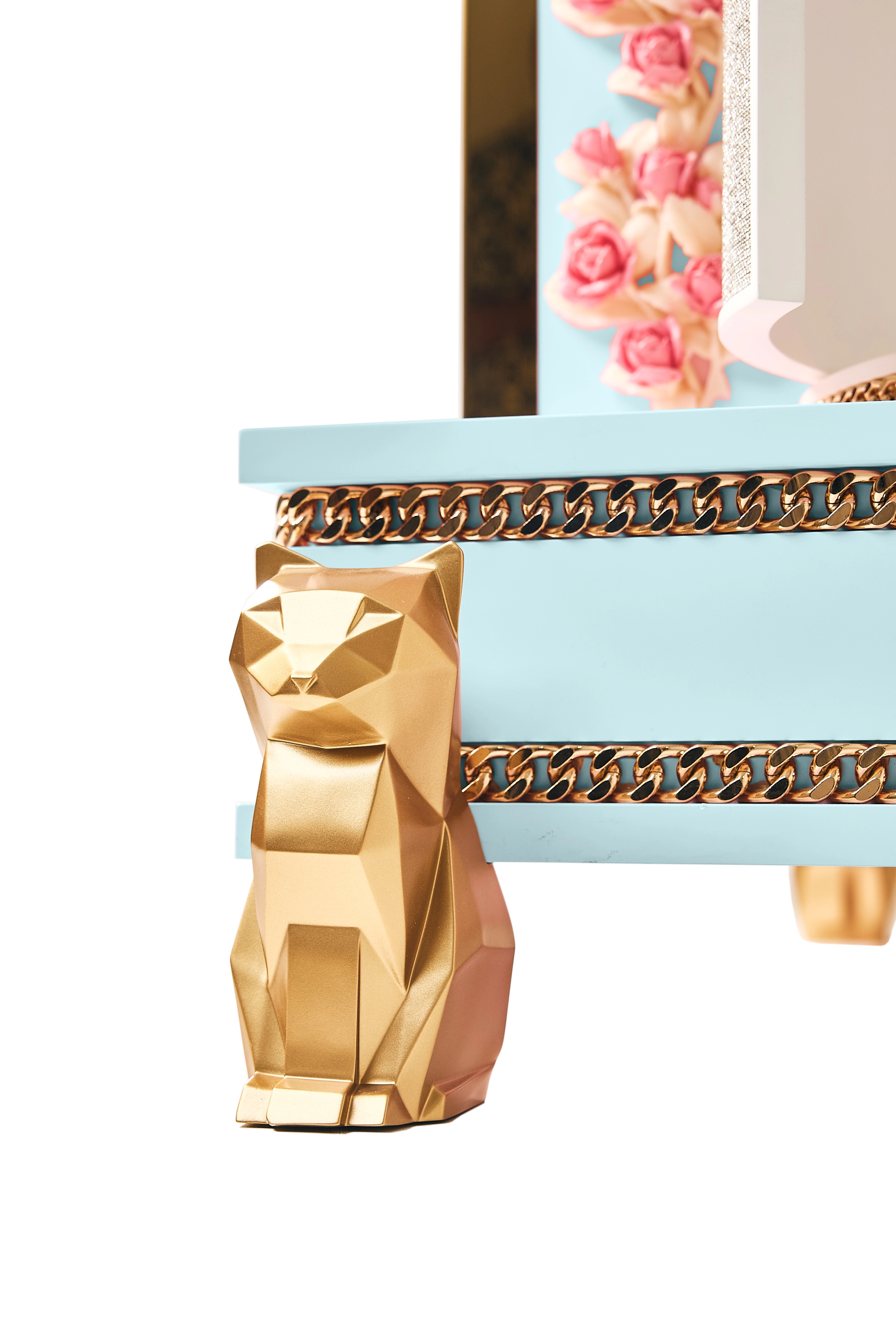 Close-up of the FUROAR luxury designer cat villa in light blue, showcasing a geometric gold cat sculpture leg, metallic curb chain trim, and delicate pink rose accents.