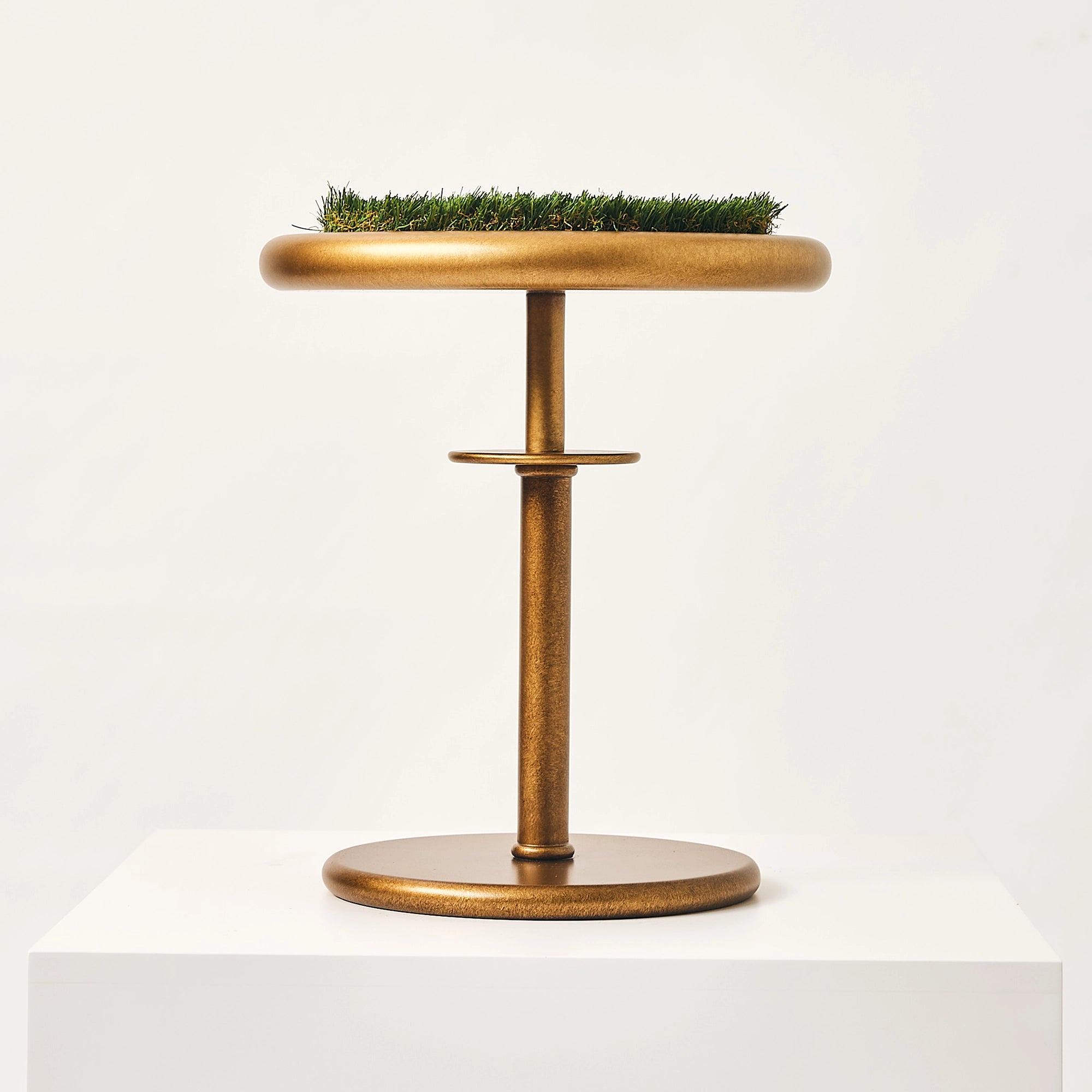 A straight profile view of the gold Regalia falcon stand with a grass turf top.